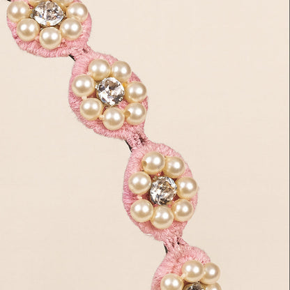 Pink beaded headband with black elastic band on a beige background