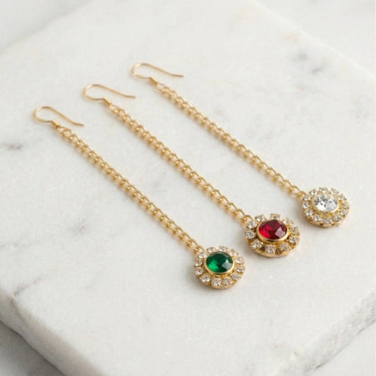 Gold earrings with gemstones on a marble surface
